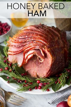 ham on a platter with cranberries and greenery for garnish