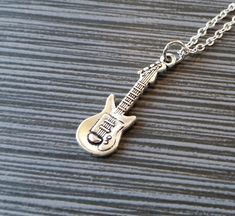 Personalized Silver Guitar Necklace!  A detailed three dimensional electric guitar charm on a bright silver chain makes the perfect gift for you or your favorite musician.The guitar charm is made from zinc alloy and measures 30 mm by 10 mm.  The chain is silver plated and measures 16" or 18" with a 1" extender.  You can also personalize your necklace with a .5" silver plated disc stamped with the initial of your choice (see last picture).  To order your necklace WITHOUT a custom stamped initial Cheap Adjustable Music-themed Necklace, Music-themed Pendant Necklaces As Gift, Music-themed Sterling Silver Necklace, Guitar Pick + Necklace Cheap, Guitar Pendant Necklace, Silver Trumpet, Football Bracelet, French Hook Earrings, Music Jewelry