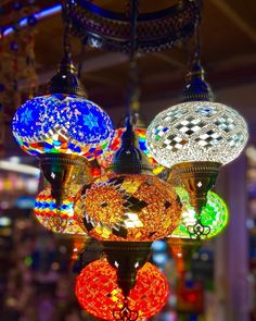 several colorful lights hanging from the ceiling in a store or restaurant, all lit up with different colors and patterns