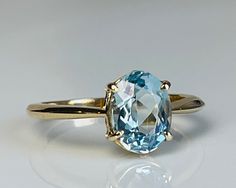 Lovely vintage genuine Aquamarine engagement ring with stunning natural earth mined Aquamarine in 14k gold. The Aquamarine is a beautiful tropical water blue with aqua green hue and is estimated to weigh 1.75 carats (~9 mm x 7 mm). The stone is an older oval cut with a smaller high table and appears to be unheated (rare!). Inside of the ring is stamped for 14k gold. Details: Ring is stamped for 14K.  Ring weighs 2.8 grams.  Currently a size 6.5 and can be sized by adding our custom sizing listin Cushion Cut Aquamarine Engagement Ring, Aquamarine And Gold Ring, Gold Aquamarine Engagement Ring, Light Blue Oval Ring With Prong Setting, Aquamarine Oval Ring, Classic Light Blue Rings For Anniversary, Classic Aquamarine Solitaire Jewelry, Classic Solitaire Aquamarine Jewelry, Oval Aquamarine Birthstone Ring Fine Jewelry