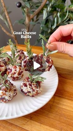 someone is holding up some appetizers on a plate with rosemary sprigs