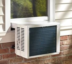 an air conditioner sitting on the side of a brick wall next to a window