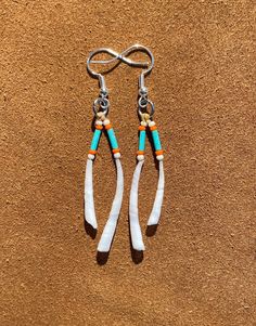 two white and blue beads hanging from hooks on a brown surface with a pair of scissors