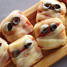 some kind of appetizer with googly eyes on it sitting on a wooden tray