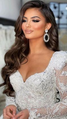 a woman in a wedding dress with long hair and big earrings on her left hand