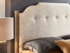 a close up of a bed with two pillows and a lamp next to the headboard