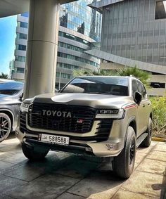 two cars parked next to each other in front of a building with tall buildings behind them