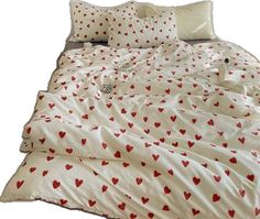 an unmade bed with red hearts on it and two pillows in the middle,