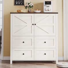 a white cabinet with doors and drawers in a living room next to a coffee maker