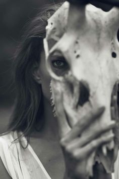 a woman holding up a fake skull to her face