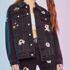 a woman wearing a black jean jacket with skulls on it