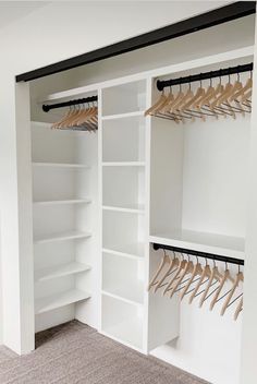 an empty closet with white shelves and wooden clothes hangers on the wall, along with carpeted flooring