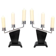 a set of four candles sitting on top of a black stand next to each other