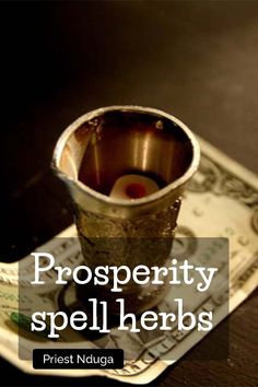 a cup sitting on top of a pile of money with the words prosperity spell herbs