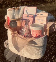 a basket filled with items sitting on top of a grass covered field next to a cup