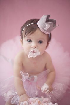 a baby girl wearing a pink tutu while eating cake