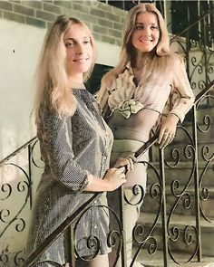 two women are standing on the stairs in dresses