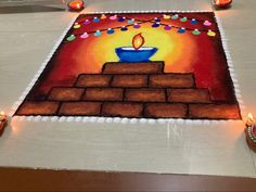 a decorated cake with lit candles on the floor in front of it and an image of a cupcake