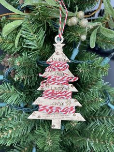 a wooden christmas tree ornament hanging from a fir tree with candy canes