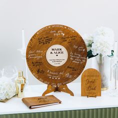 a wooden wheel with names on it sitting on a table next to some white flowers