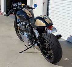 a black and gold motorcycle parked in front of a garage