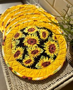 four yellow sunflowers are on the table next to a potted plant