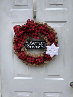 a red and black wreath with a snowflake on the front door that says let it snow