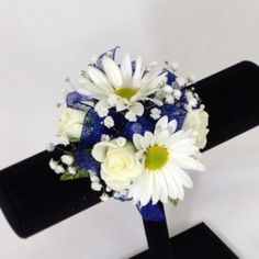 a blue and white bridal bouquet sitting on a black display stand against a white wall