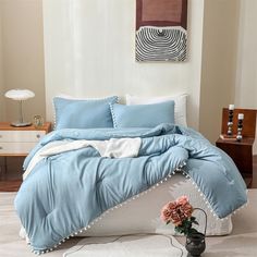 a bed with blue comforters and pillows in a white room next to a table