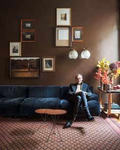 a man sitting on top of a blue couch in a living room next to a table