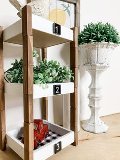 a wooden shelf with plants and numbers on the top, in front of a white potted planter