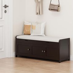 there is a bench and coat rack on the wall in this entryway with wood flooring