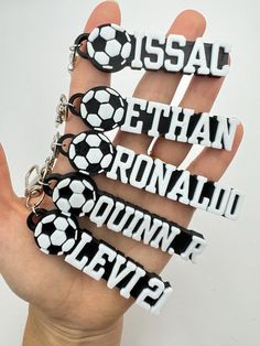 a hand holding several key chains with soccer balls on them