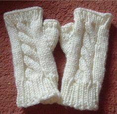 two white knitted mittens sitting on top of a pink carpet