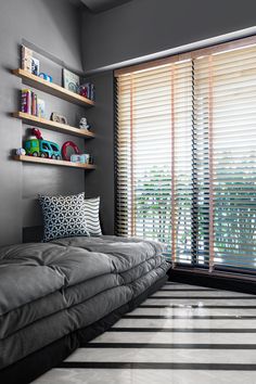 a bed sitting in the middle of a room next to a window with blinds on it