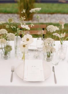 the table is set with white flowers and silverware