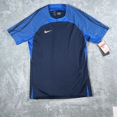 Introducing the Nike Men's Dri-Fit Strike Top, a stylish and functional addition to any athlete's wardrobe. This pullover T-shirt features a crew neck and short sleeves, with a slim fit that flatters the wearer's physique. The Nike logo is prominently displayed in blue on the shirt's front, adding a touch of personality to the garment. This top is machine washable and comes in size L. It is perfect for soccer and football and is suitable for wear in all seasons. The Nike Dri-FIT product line ensures that the garment is moisture-wicking, keeping the wearer cool and comfortable during physical activity. Trash Fashion, Seasons Winter, Nike Pro Combat, Nfl Outfits, Fitted Turtleneck, Black Graphic Tees, Dri Fit Shirt, Physical Activity, Soccer Football