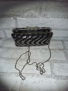 This glitzy little clutch is perfect for the holidays. It is about 7 inches long and 4 inches tall. Lift the top bow and it opens wide enough to fit your hand. All the rhinestones are present and accounted for on the bow clasp. The body of this purse is sequins, sequins, sequins.  The chain handle is 24 inches from the purse so about 48 total. Long enough to cross over most bodies. When not in use it tucks completely inside the clutch. I cannot find a maker tag on this purse. A great gift or a little glam for yourself. Glamorous Silver Glitter Clutch, Glamorous Evening Bag With Chain Strap For Gift, Glamorous Evening Clutch With Glitter, Glamorous Glitter Clutch For Evening, Glitter Clutch Evening Bag, Glitter Clutch Evening Bag Gift, Chic Evening Clutch With Glitter, Elegant Glitter Evening Bag As Gift, Silver Glitter Clutch For Events