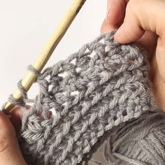 someone is crocheting the ends of their hand knitted scarf with a wooden knitting needle