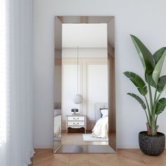 a large mirror sitting on top of a wooden floor next to a potted plant