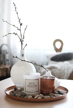 a white vase sitting on top of a table next to a candle and some rocks