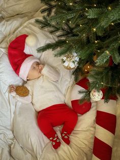 a baby is sleeping next to a christmas tree