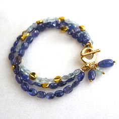 Glittering, vibrantly hued genuine polished natural periwinkle hued tanzanite, one of the rarest and most prized of all gemstones, sparkles on this strand in a beautiful bright striking splash of color! A linked strand of silvery blue baroque pearls pick up the colors of the tanzanite. A 14k gold lobster clasp secures this one of a kind piece at 7 - 8.5 inches long, however further adjustments can be made, please inquire. Blue Bracelet With Gemstone Accents As Gift, Handmade Tanzanite Blue Jewelry, Blue Bracelets With Gemstone Accents As A Gift, Blue Bracelets With Gemstone Accents For Gift, Blue Faceted Amethyst Jewelry, Faceted Blue Amethyst Jewelry, Elegant Blue Amethyst Gemstones, Blue Tanzanite Gemstone Bracelets, Blue Tanzanite Bracelet Jewelry