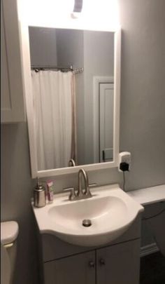 a white sink sitting under a bathroom mirror