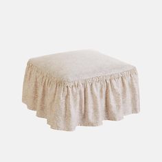 a white ottoman with a ruffled skirt