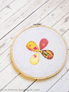 an embroidery project with flowers and hearts on the hoop, sitting on a wooden surface