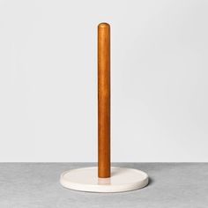 a tall wooden pole sitting on top of a cement floor next to a white wall