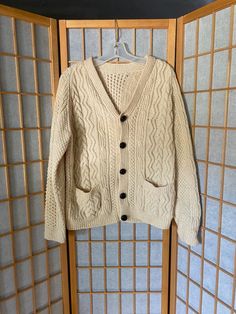 Lovely 1980’s cream wool cardigan with shiny black buttons. Small hole in the front right chest, shown in photo. Two front pockets. Heavy tradition Irish sweaterSize largeChest: 42”Shoulder to hem: 26.5” Winter Cream Cardigan With Pockets, Cream Button-up Winter Sweater, Cream Wool Cardigan With Button Closure, Cream Wool Sweater With Button Closure, Retro Cream Cardigan For Winter, Retro Cream Winter Cardigan, Vintage Beige Winter Cardigan, Retro Cream Cardigan For Fall, Vintage Wool Cardigan With Pockets