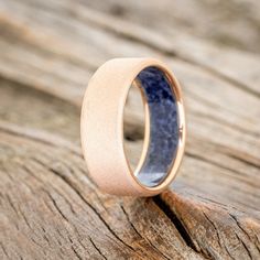 a wedding ring with a blue stone in the center on top of a wooden surface