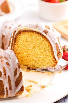 a bundt cake with white icing and strawberries in the background on a plate